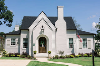 From profile of a recently remodeled home in Cullman, AL. A white cottage home with a brown stained front door, chimney, and American flag.